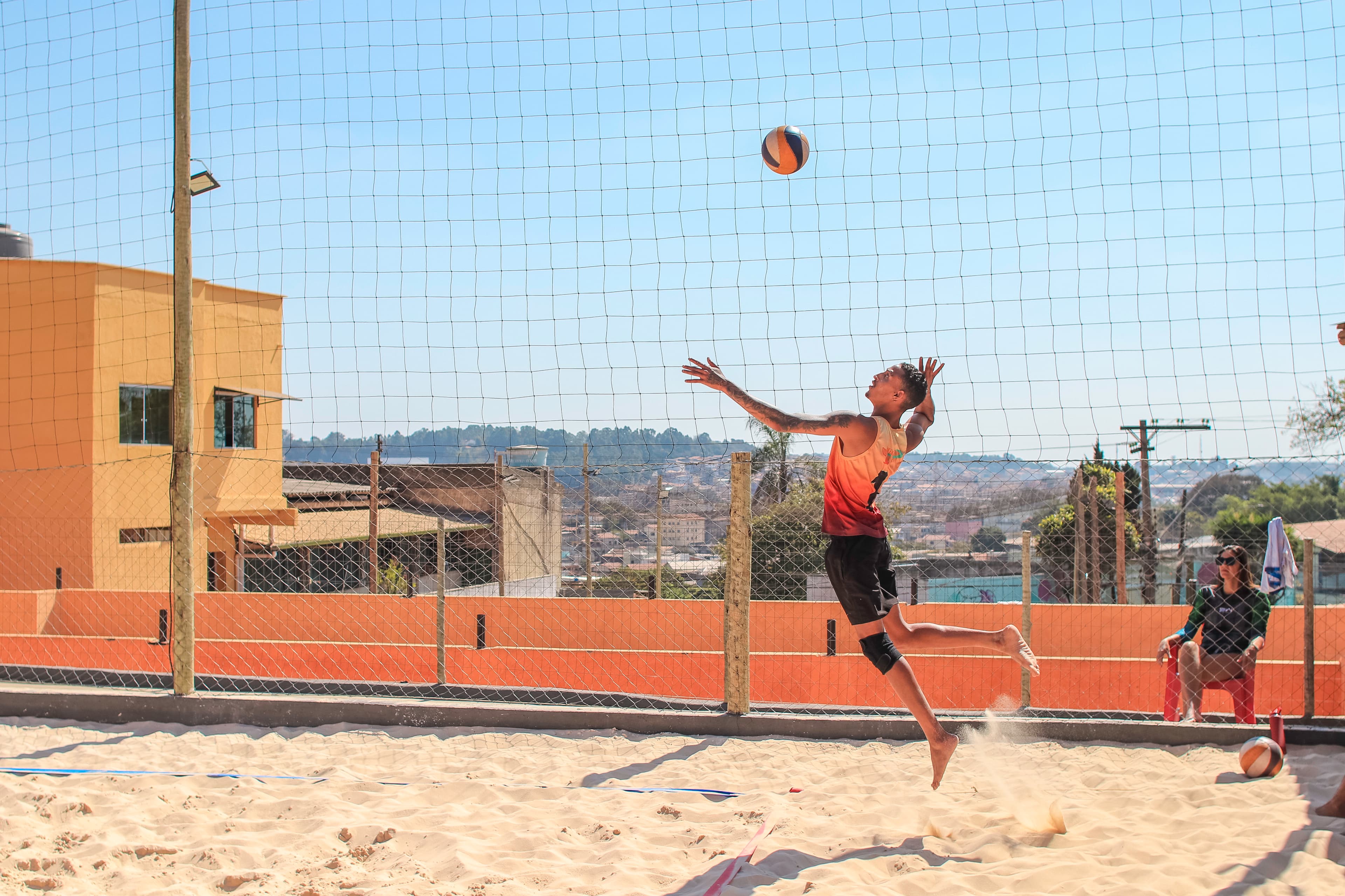 Atleta sacando em quadra de areia durante evento diurno